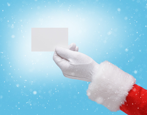 Hand in costume Santa Claus is holding business card / studio shot of man's hand holding empty blank / Merry Christmas & New Year's Eve concept / Closeup on blurred blue background.