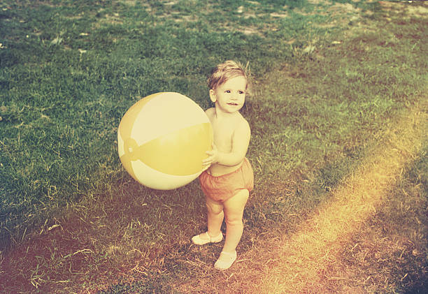 baby ragazza con palla da spiaggia - 1970s style immagine foto e immagini stock