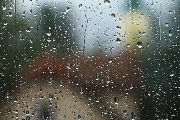 Rain drops on window with house and church in background