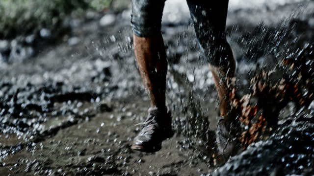 SLO MO DS Female legs running across a muddy puddle at night