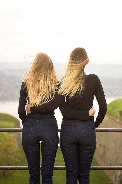 Two identical teenage girlfriends, shot from back. Rear view Two identical teenage girlfriends, shot from back. Rear view blond hair fine art portrait portrait women stock pictures, royalty-free photos & images