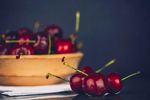 Fresh organic cherries in wood bowl on black slate