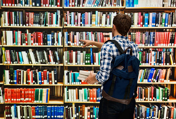istock Rear view of student pointing at books 502556036