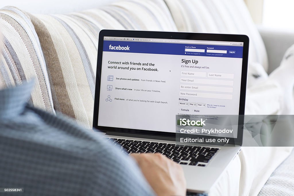 man sitting at the MacBook retina with site Facebook Simferopol, Russia - July 9, 2014: Facebook the largest social network in the world. It was founded in 2004 by Mark Zuckerberg and his roommates during training at the Harvard University. Social Media Stock Photo