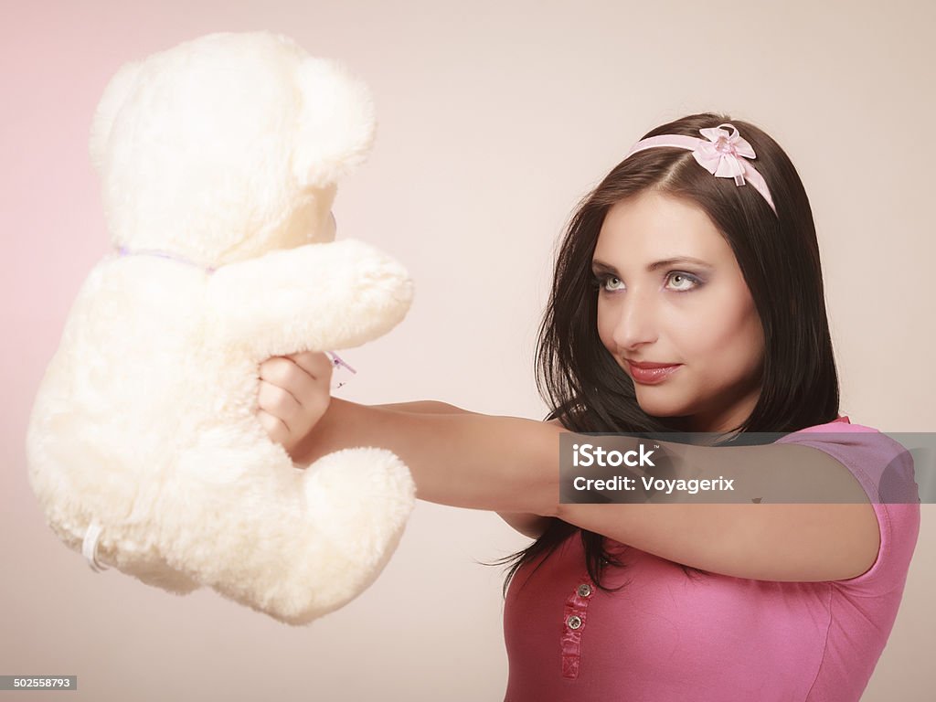Childish young woman infantile girl in pink hugging teddy bear Portrait of childish young woman with headband holding toy. Infantile girl hugging teddy bear on pink. Longing for childhood. Studio shot. Absence Stock Photo