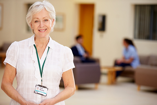 Portrait Of Female Consultant In Hospital Reception Looking At Camera Smiling
