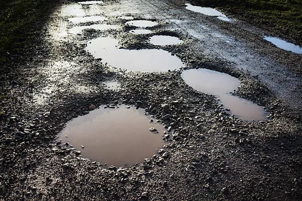 A wet rural road with bad potholes.
