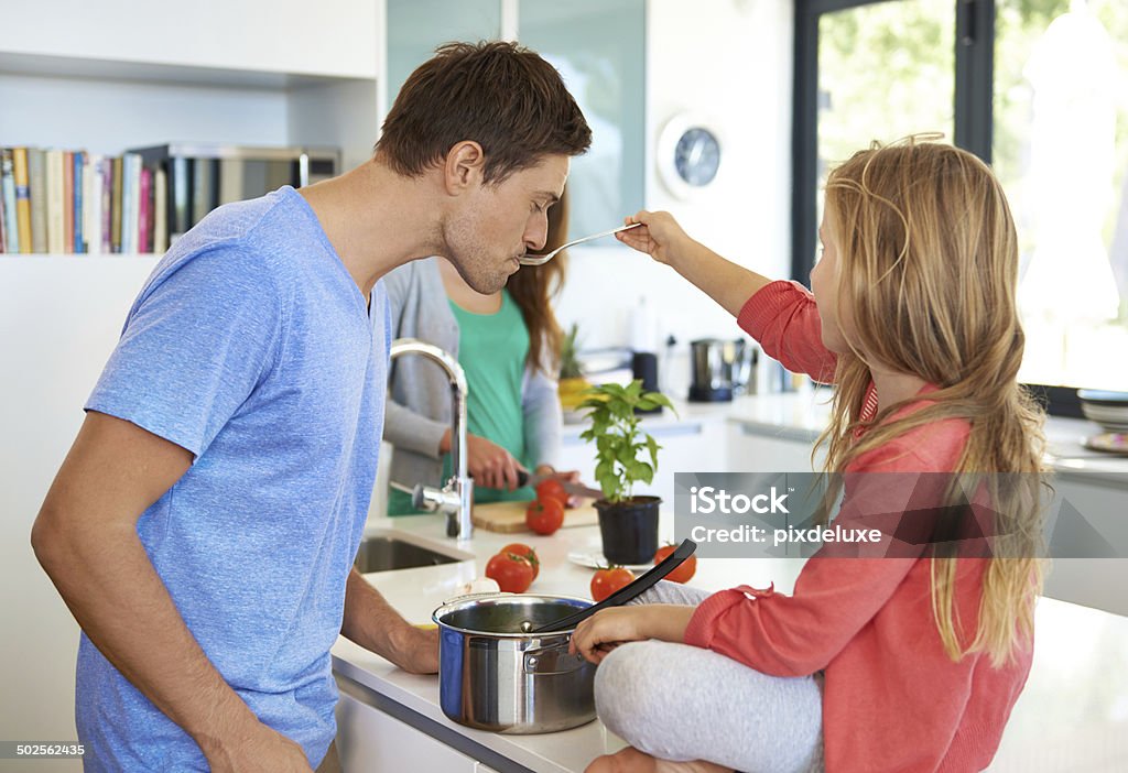 His masterchef was at the top of her game A shot of a family preparing a meal together as the young girl gives her dad a taste of the food she made Adult Stock Photo