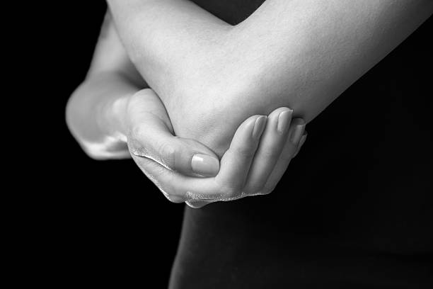 Pain in the elbow joint Unrecognizable woman holds her elbow joint, acute pain in the elbow, monochrome image elbow photos stock pictures, royalty-free photos & images
