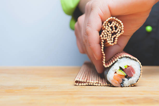 rolling up sushi closeup of chef hands rolling up sushi on a bamboo mat sushi photos stock pictures, royalty-free photos & images
