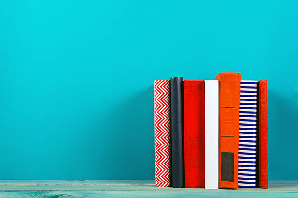 Row of colorful hardback books, open book on blue background
