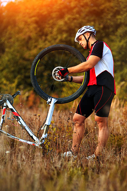 istock cyclist repairs bicycle on the meadow 502581316