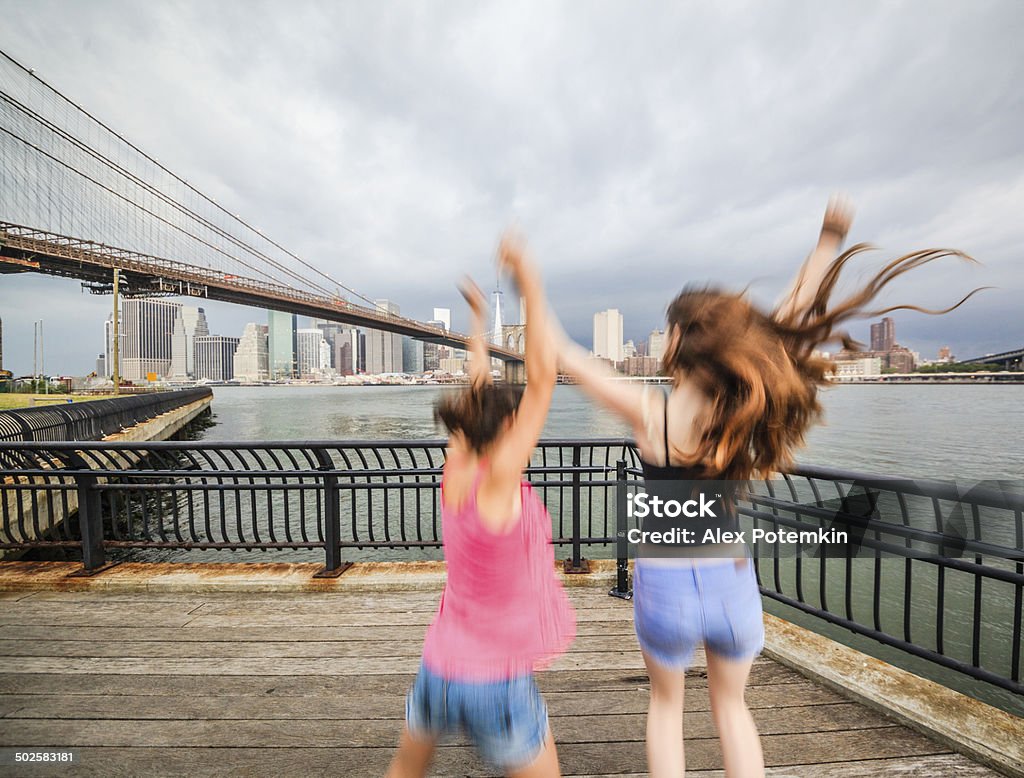 Two girls, sisters, looking to Manhattan under thunderstorm Two girls, sisters, dancing and playing at the waterfront, Brooklyn, New York  Happiness Stock Photo