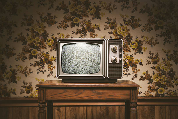 Retro Television and Wallpaper An old T.V. from the 1980's sits on a wood table in a vintage styled living room, floral wallpaper and wood paneling on the wall in the background.  Horizontal image with copy space. wood paneling retro stock pictures, royalty-free photos & images