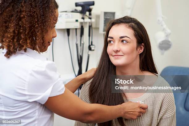 Female Consultant Examining Teenage Patient In Hospital Stock Photo - Download Image Now