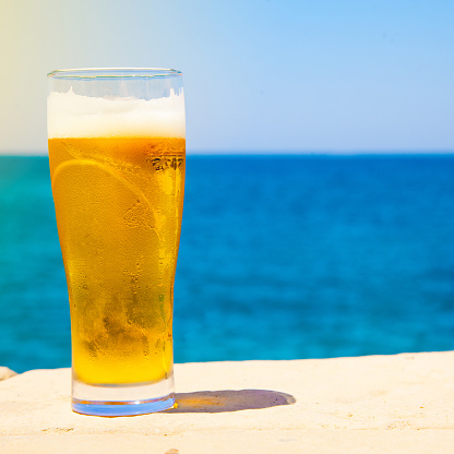 square photo of Glass of beer at summertime near sea