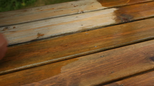 Hand Applying Deck Stain with a Large Paintbrush