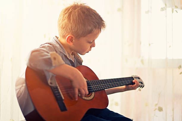 petit garçon pratiquant le guitare. - guitar child music learning photos et images de collection