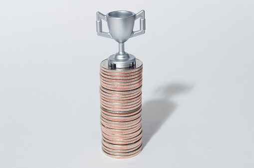 Stack of coins with the trophy on the top 