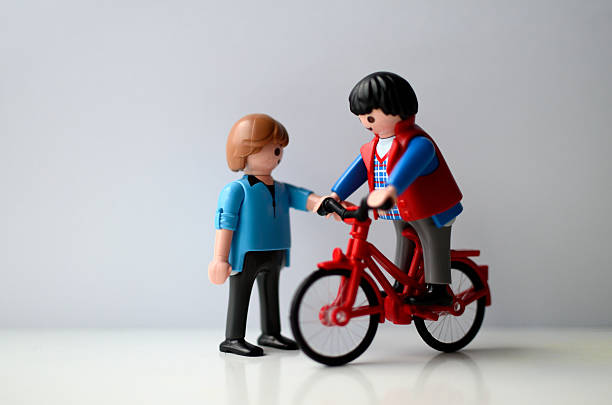 Daimiel, Spain - December 12, 2015: Two men, one on a bike and talking to another man. A playmobil es a children figure toy on white background, isolated. 