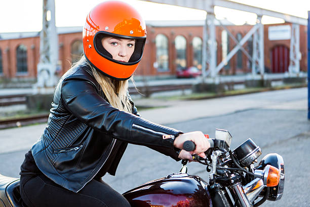Cute girl with blond hair with orange motorcycle helmet. Outdoor, urban scene.