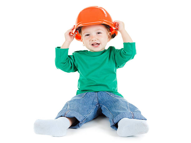 istock Little child plays with orange construction protective helmet  on white 502613508