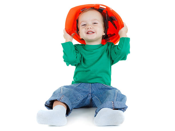 istock Little child plays with orange construction protective helmet  on white. 502613514