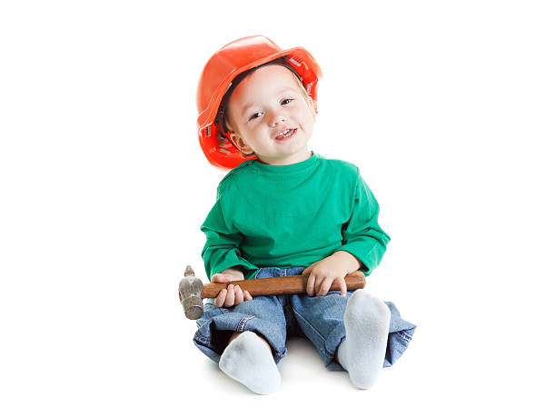 istock Child plays with hammer and construction protective helmet  on white 502614314