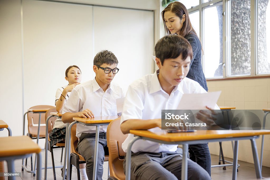 Teacher distributing a school exam Teacher distributing a school exam to students in a Chinese secondary school. Giving Stock Photo