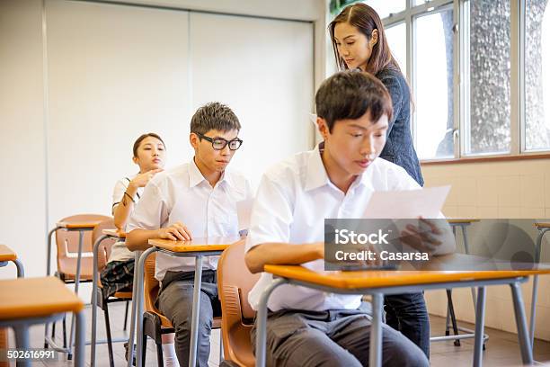 Teacher Distributing A School Exam Stock Photo - Download Image Now - Giving, Teacher, 16-17 Years