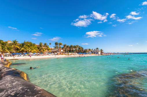 Isla Mujeres, Mexico - April 21, 2014: tourists enjoy tropical sea on famous Playa del Norte beach in Isla Mujeres, Mexico. The island is located 8 miles northeast of Cancún in the Caribbean Sea.