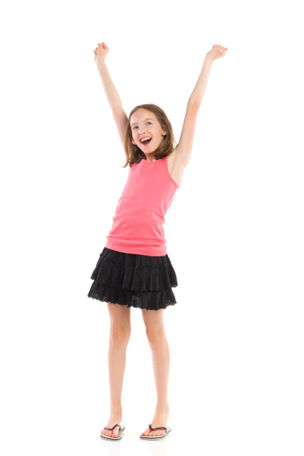 Smiling little girl celebrating success with arms raised. Full length studio shot isolated on white.