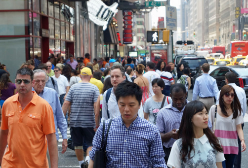 New York, NY, USA – July 2, 2014: A diverse crowd of people cross the street near Times Square in midtown Manhattan.