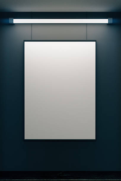 istock Blank picture frame on grey wall with glowing lamp 502658582