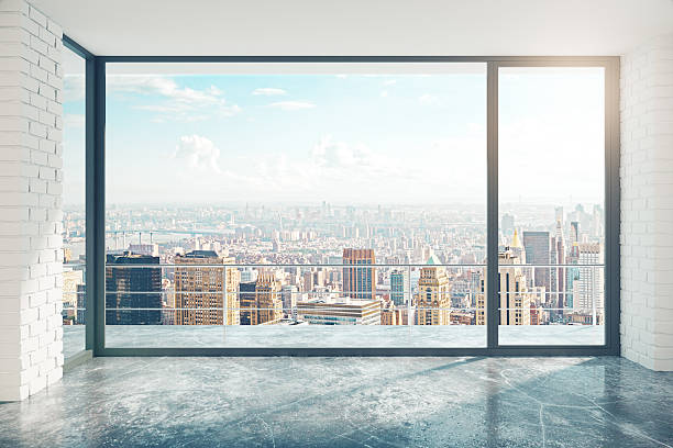 Empty loft style room with concrete floor and city view