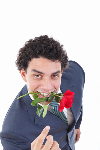 confident man seducer in a suit holding a red rose in his mouth with a seductive view or look while pointing his hand or finger and called to come