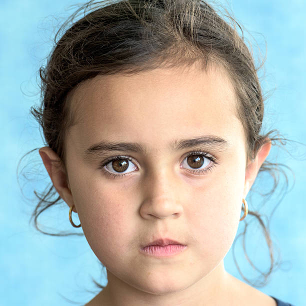 Portrait of sad crying emotional cute little girl looking at camera with face of deep sadness and sorrow outdoors. Sad child with blue eyes, copy space.