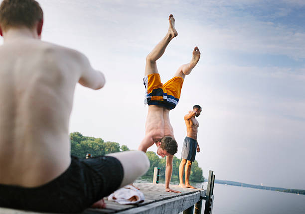Young man doing a handstand on a lake Pier