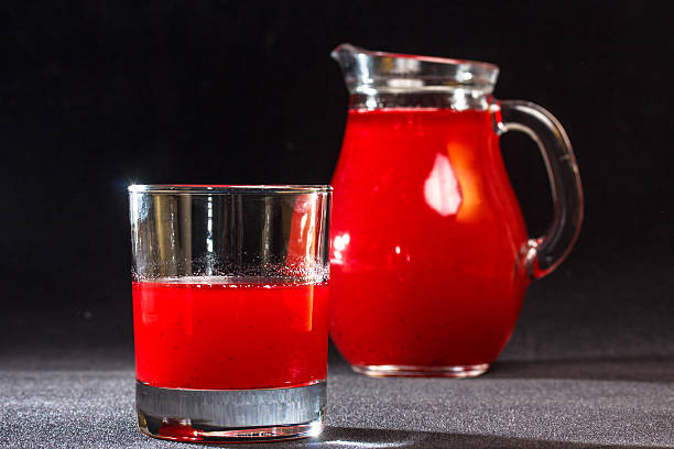 red drink in einem glas und mit einem krug. - кувшин stock-fotos und bilder