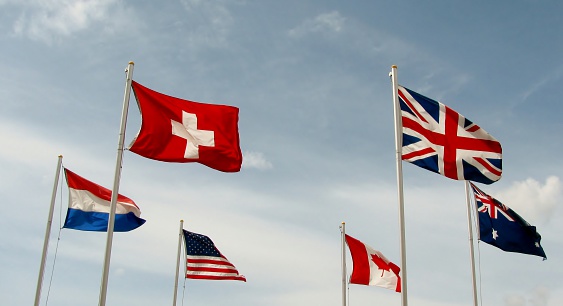 International flags fly side by side against the blue sky