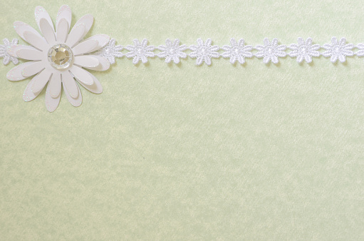 Pretty ribbon border on green colored paper that can be used as a background for scrapbooking, cards, or invitations