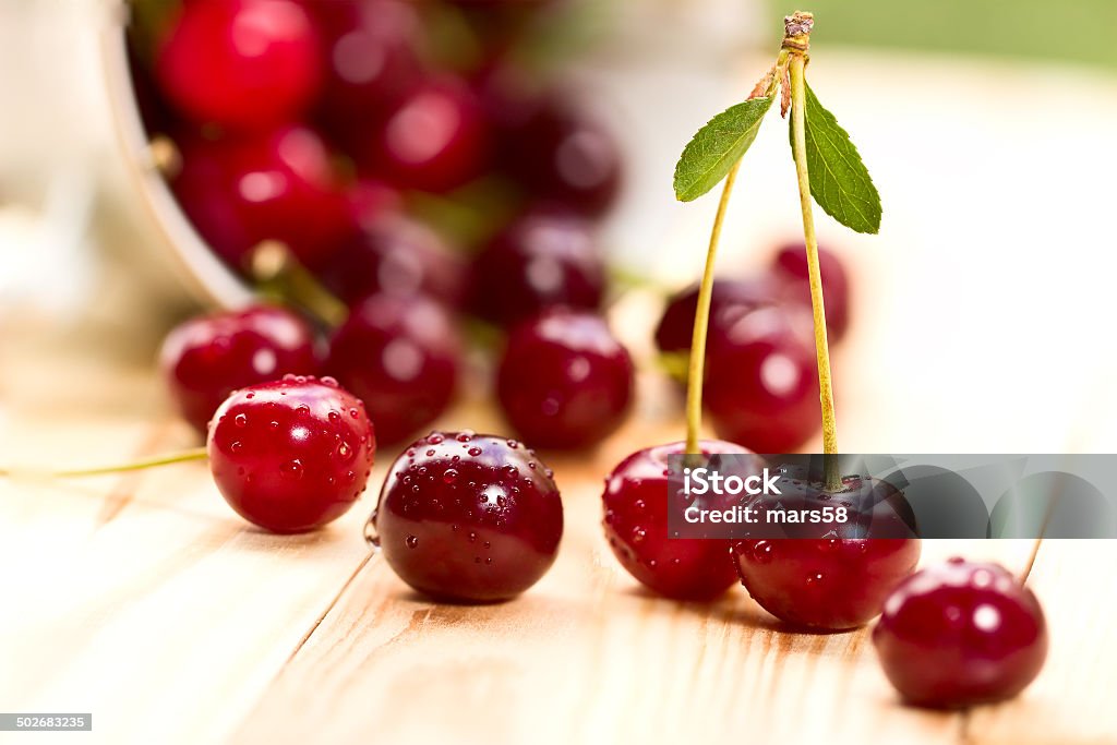 Cherries on wooden table with water drops macro background Cherries on wooden table with water drops macro August Stock Photo