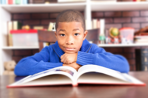 Back to school time!  African descent, elementary boy enjoys reading at school.