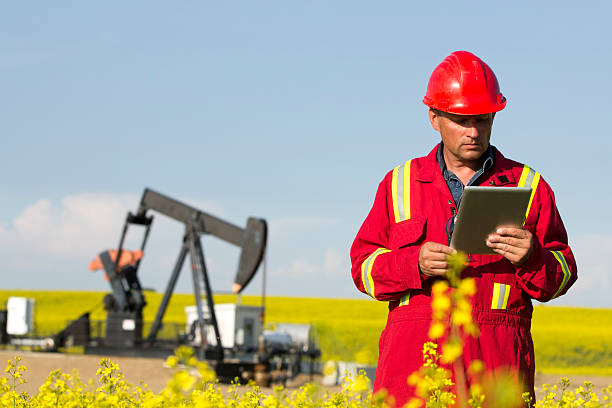 pracownik przemysłu naftowego i canola pole - oil industry digital tablet manual worker mining zdjęcia i obrazy z banku zdjęć