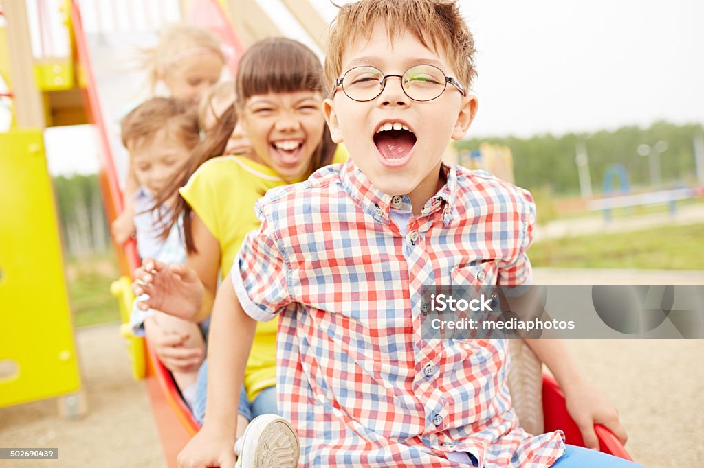 Real joy Joyful kids going down the slide on school playground Child Stock Photo