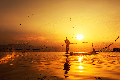 throwing fishing net during sunset