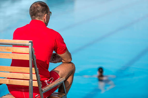 Lifeguard Lifeguard in chair, overlooking swimming pool Lifeguard stock pictures, royalty-free photos & images