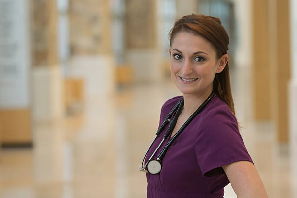 Beautiful Nurse An attractive, young, female, medical professional wearing burgundy scrubs and a stethoscope around her neck. image contains bokeh and copy space. red medical scrubs stock pictures, royalty-free photos & images