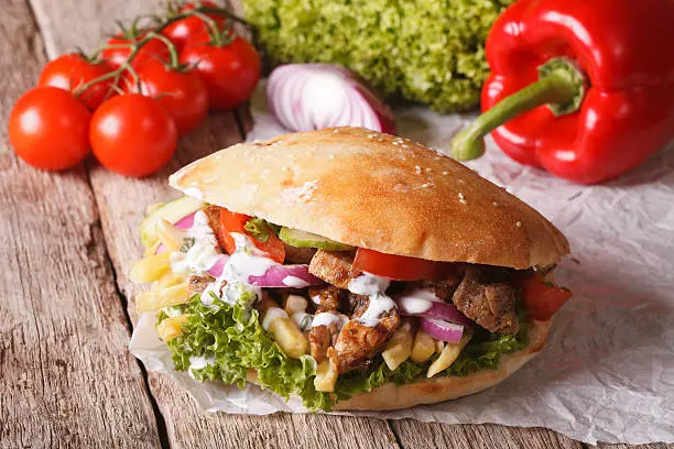 Fast Food: Doner kebab with meat, vegetables and french fries close-up on the table. horizontal