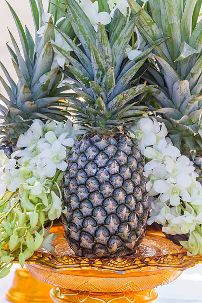 Pineapple with flowers on a golden tray with pedestal.